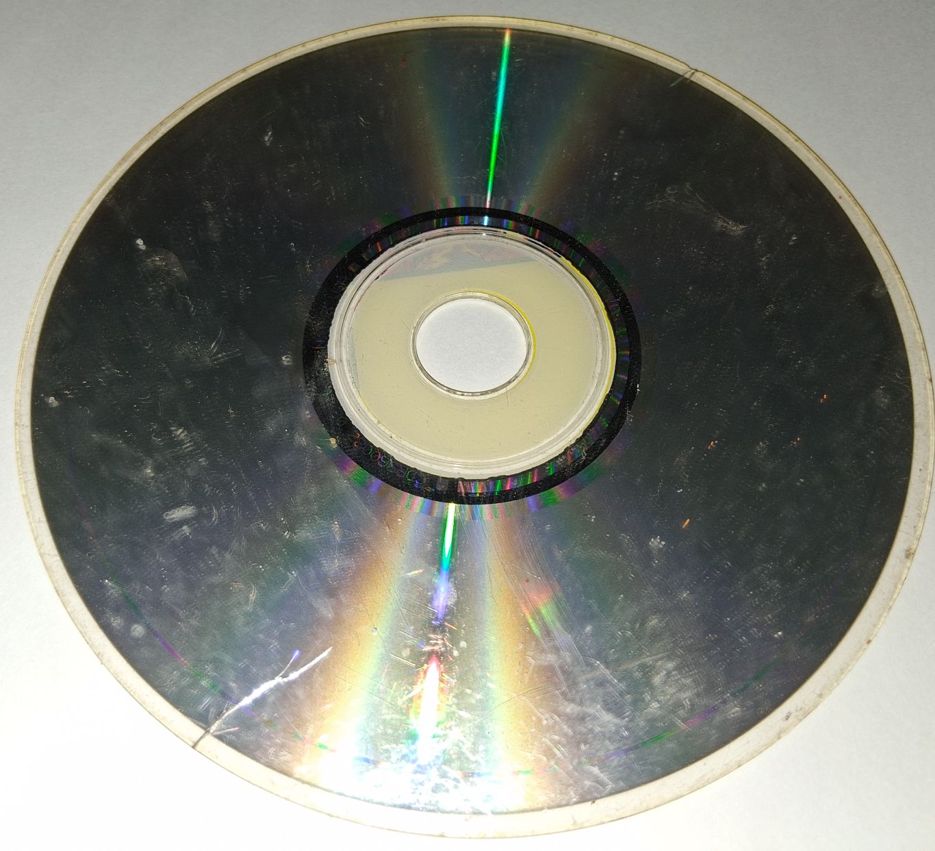 Badly scratched and scuffed dirty CD with a small crack in the edge