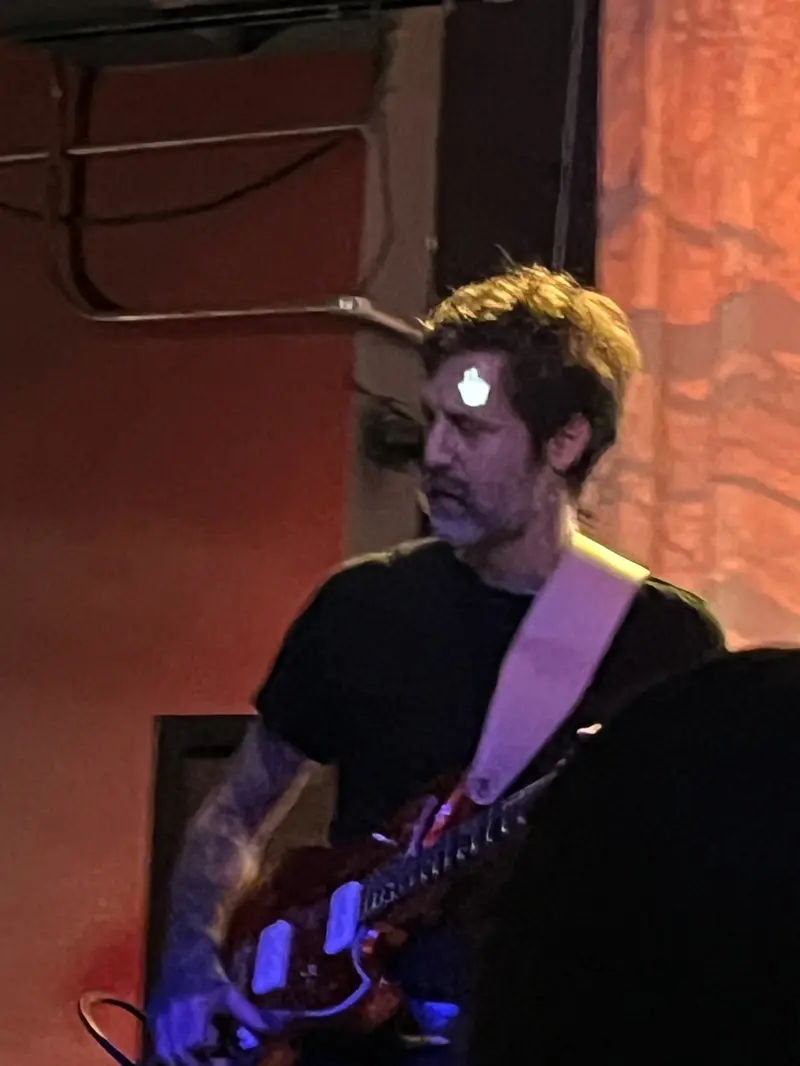 Guitarist on stage with the projection of a mouse pointer on his face