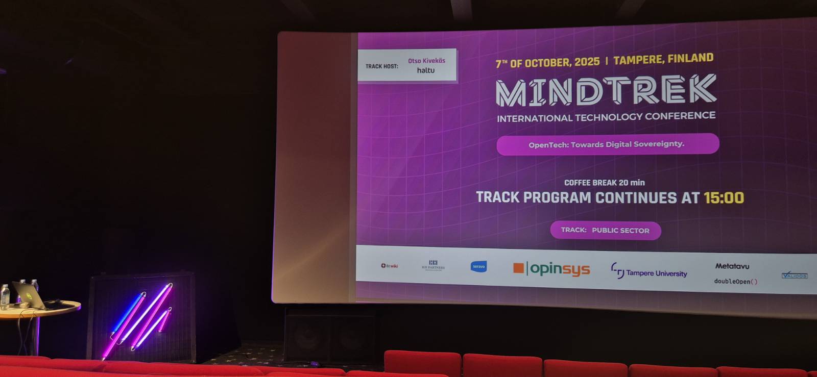 Mindtrekin yksi auditorioista. Seinällä valkokangas, johon on heijastettu tapahtuman tietoja.