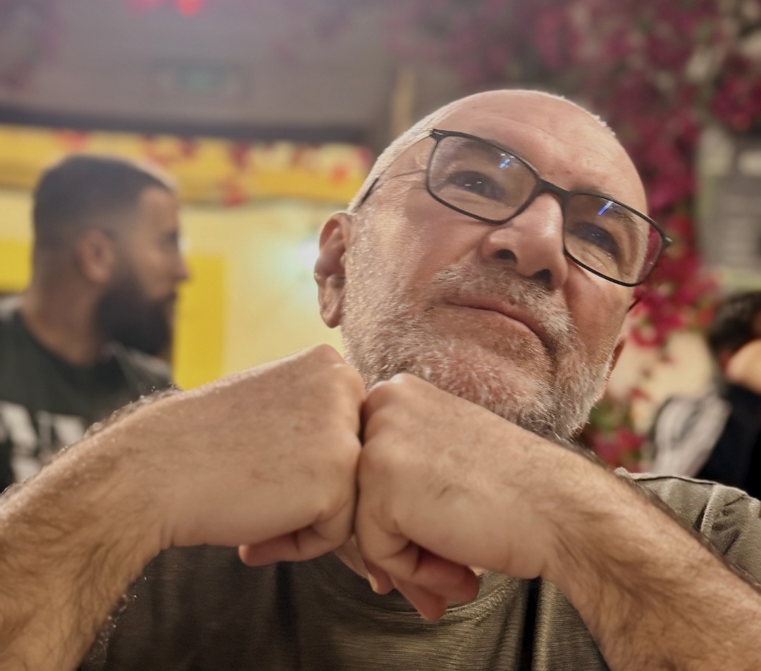 Foto di me a cena in un patio di Cordoba, Spagna, aprile 2026. Inquadratora a mezzo busto mentre guardo in alto, le mani sono davanti a me con i pugni accostati.