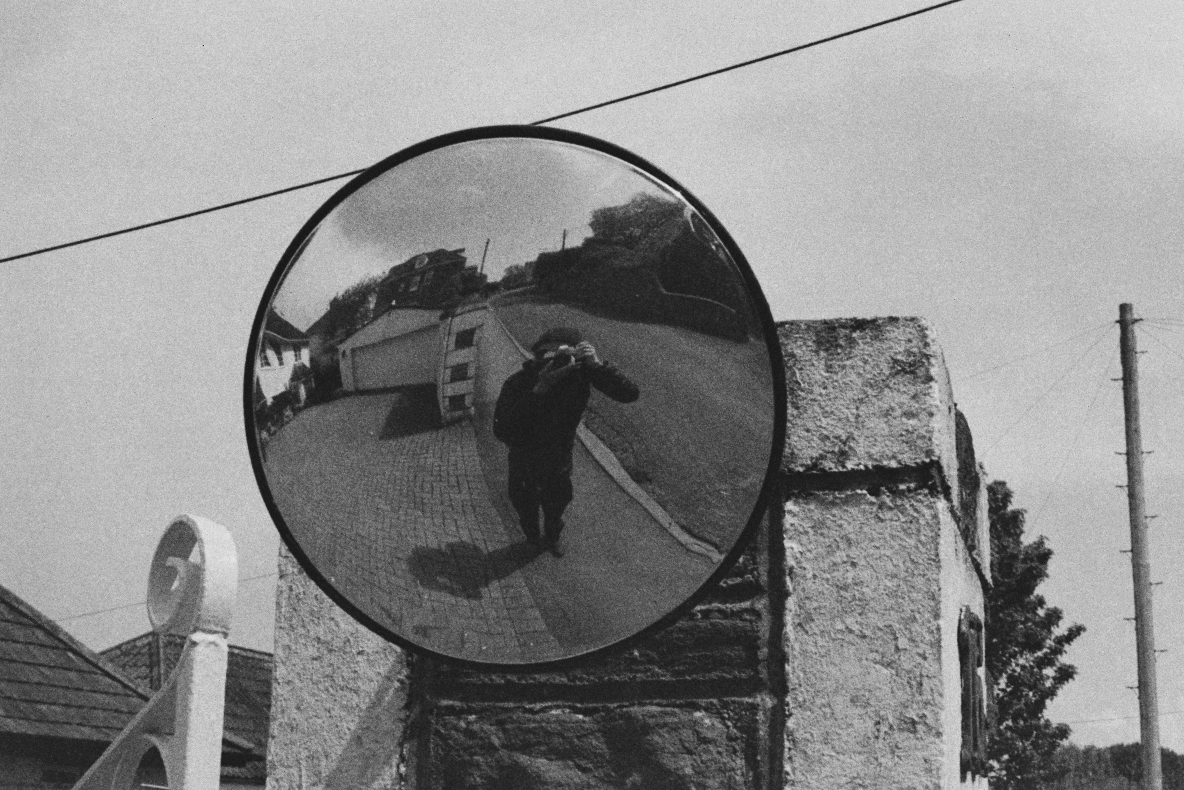 black and white photo of me in the street taking a selfie in a street mirror