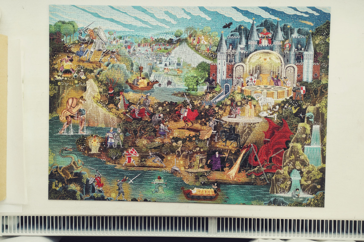 A horizontal colour photograph of a completed puzzle on a windowsill. The picture depicts various episodes and characters from the arthurian legends.